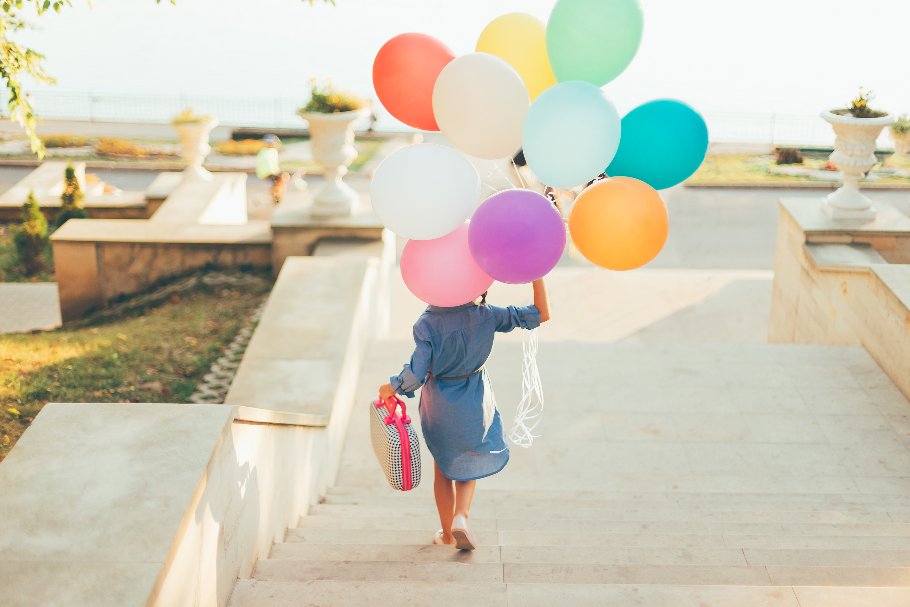 girl running stairs holding colorful balloons